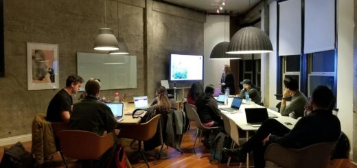 Diverse team collaborating in a modern office setting with laptops and presentation screen.